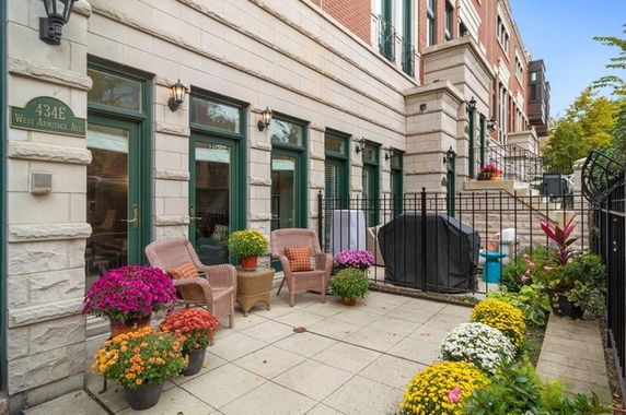 Front view of a multi-story townhouse with a terrace and potted plants.