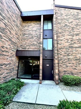 Front view of a brick building entrance with large windows and a glass door.