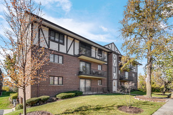 Front view of a three-story brick apartment building with balconies.