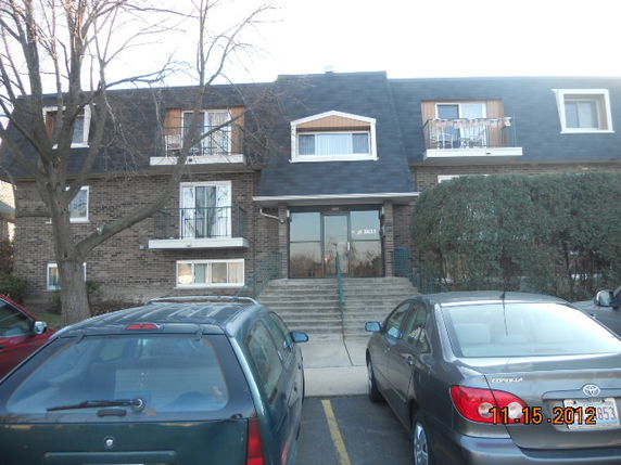 Front view of a multi-story residential building with a brick facade and a gabled roof.