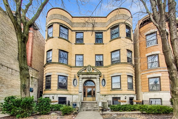 Front view of a three-story brick apartment building with decorative entrance.
