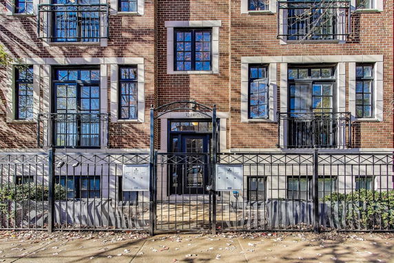 Front view of a multi-story brick building with iron railings and entrance gate.