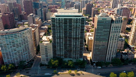 Front view of a tall residential building with multiple balconies in a cityscape.