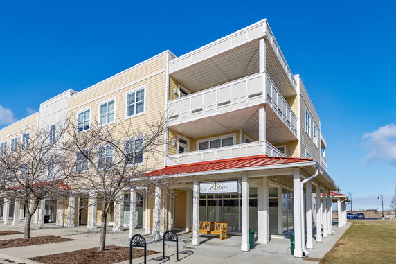 Front view of a multi-story building with balconies and a red roof.