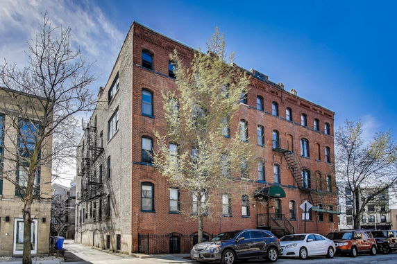 Front view of a multi-story brick building with fire escapes.