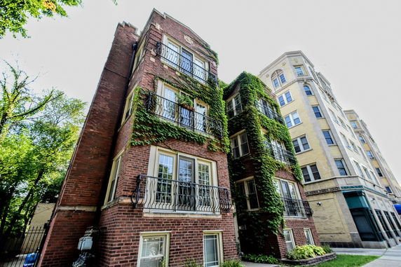 Front view of a multi-story brick apartment building with ivy-covered walls.