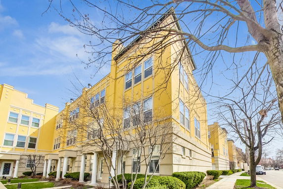 Front view of a yellow multi-story building with large windows.