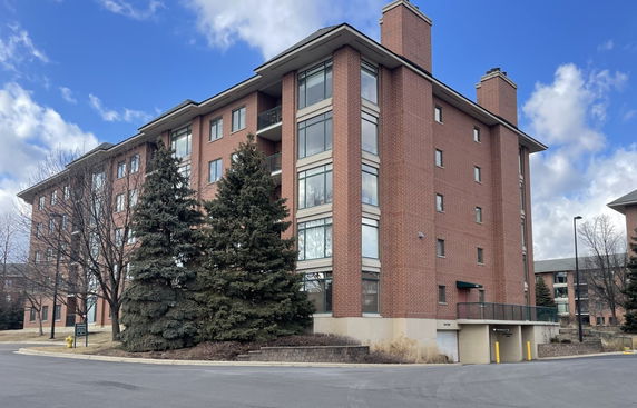 Front view of a multi-story brick building with large windows and chimneys.