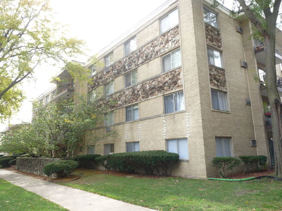 Front view of a multi-story apartment building with brick exterior and balconies.