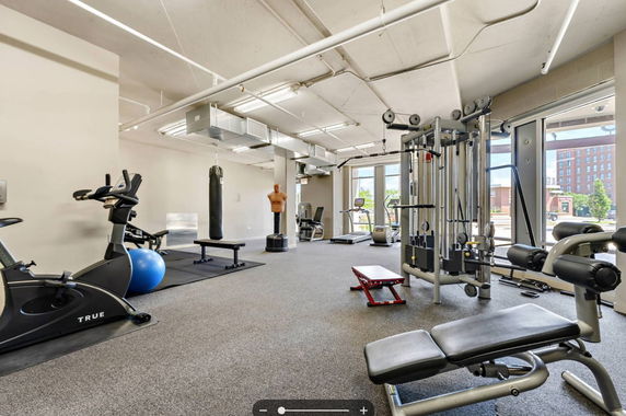 Interior view of a gym with exercise equipment including stationary bikes, weight machines, and a punching bag.