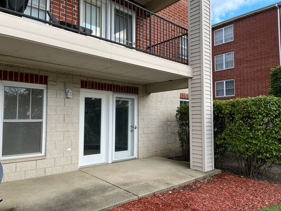 Front view of an apartment building with a balcony and patio area.