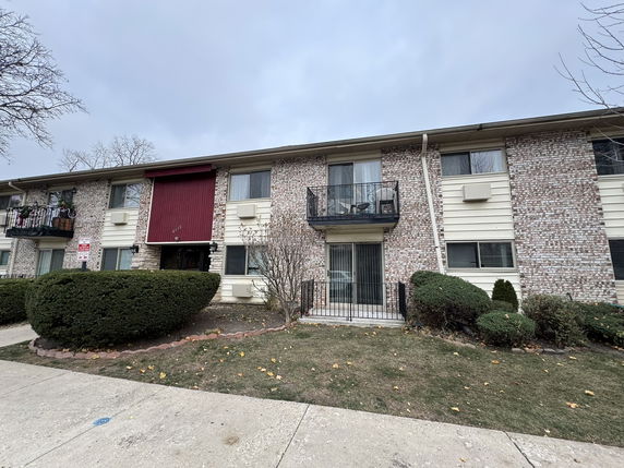 Front view of a two-story apartment building with balconies and a brick facade.