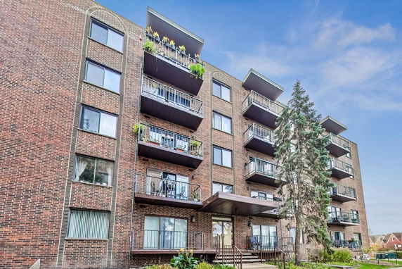 Front view of a multi-story brick apartment building with balconies.