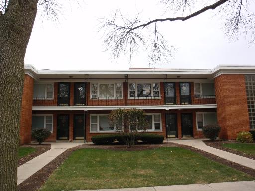 Front view of a two-story apartment building with brick facade and balconies.