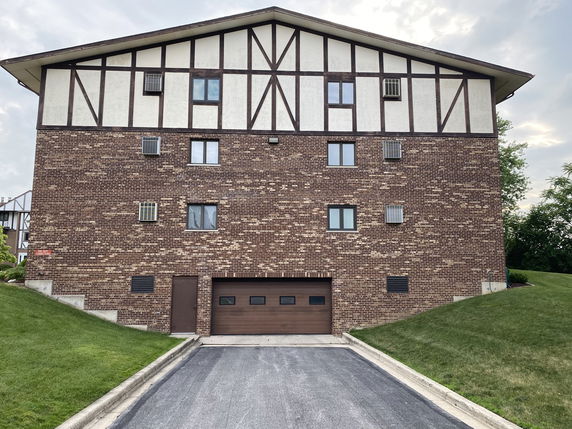 Front view of a multi-story building with brick walls and a gabled roof.