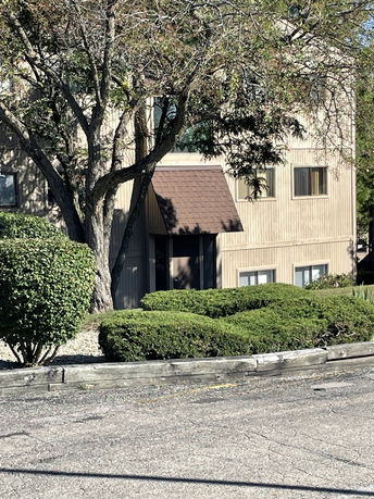 Front view of a two-story building with large windows and a brown awning.