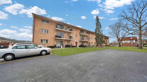 Front view of a three-story brick apartment building with balconies.