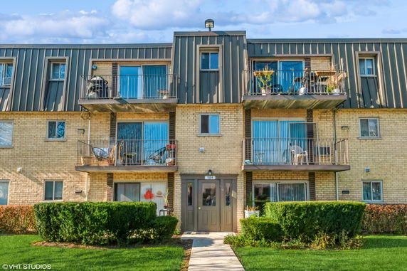 Front view of a three-story apartment building with balconies and a central entrance.