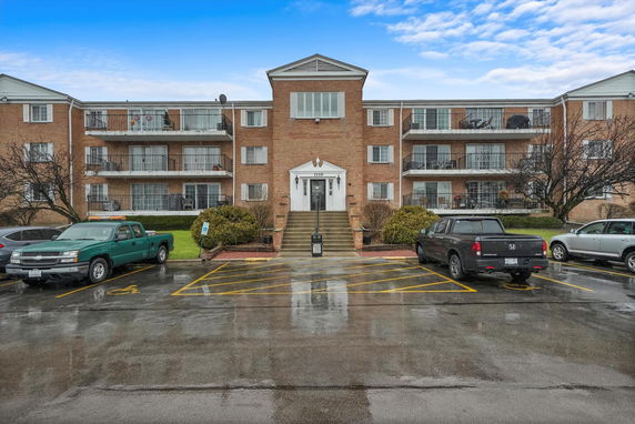 Front view of a three-story brick residential building with balconies.