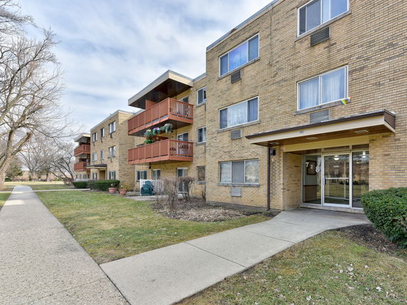 Front view of a three-story apartment building with balconies.