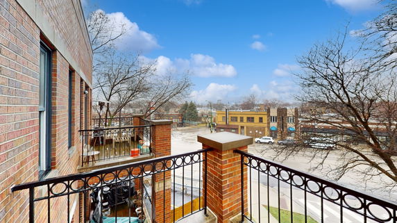 View from a building's balcony overlooking a street and surrounding buildings.