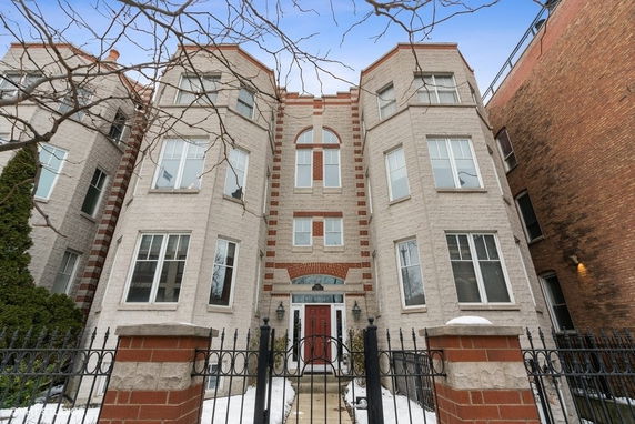 Front view of a three-story residential building with a central entrance and bay windows.