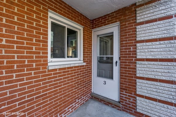 Front view of a house entry with brick walls and a door marked with the number 3.