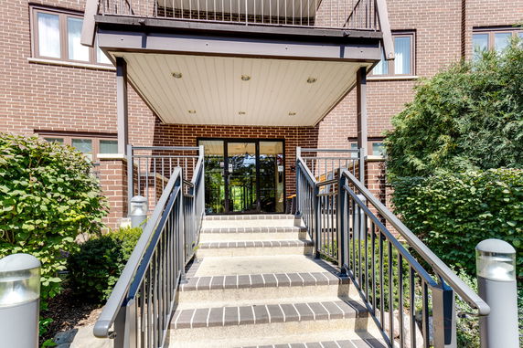 Front view of a building entrance with stairs and glass doors.