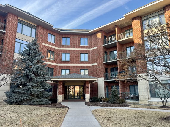 Front view of a multi-story residential building with brick facade and balconies.