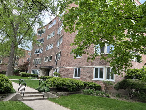 Front view of a multi-story brick apartment building with large windows.