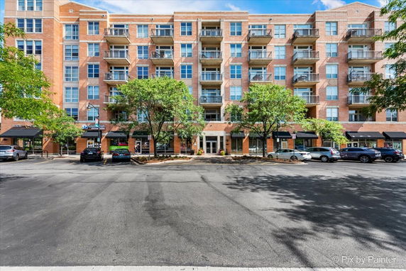 Front view of a multi-story apartment building with balconies and ground-level commercial spaces.