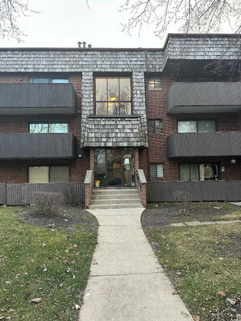 Front view of a multi-story brick apartment building with balconies.
