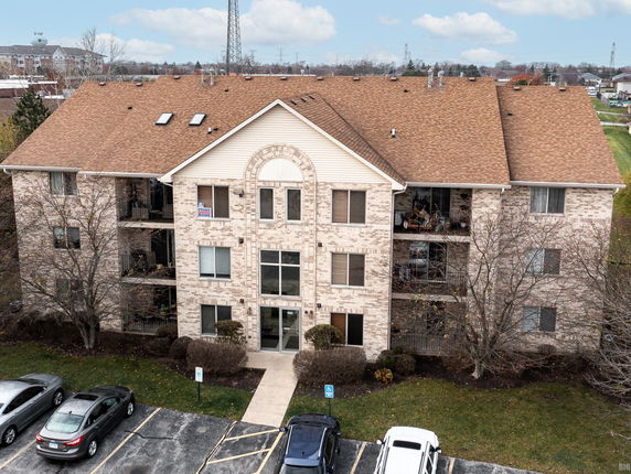 Front view of a multi-story brick apartment building with parking area in front.