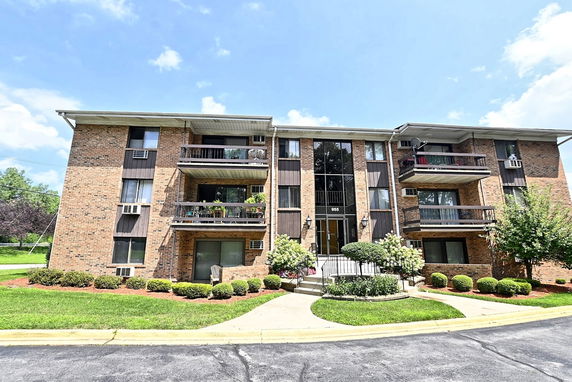 Front view of a three-story brick apartment building with balconies.