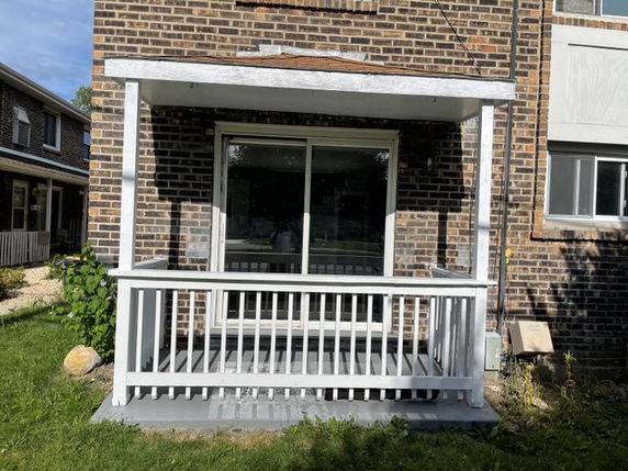 Front view of a brick house with a small porch and sliding glass door.