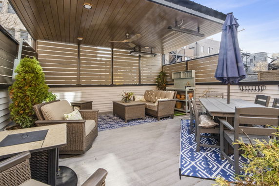 Rooftop with seating area, dining table, and decorative plants.