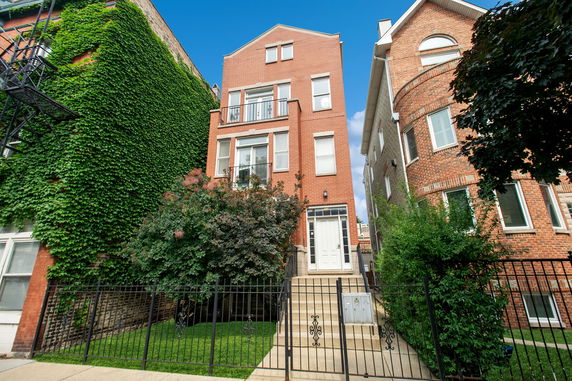 Front view of a multi-story brick house with steps leading to the entrance.