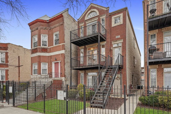 Front view of a multi-story brick building with balconies and exterior stairs.