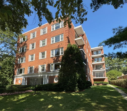 Front view of a multi-story brick residential building with balconies.
