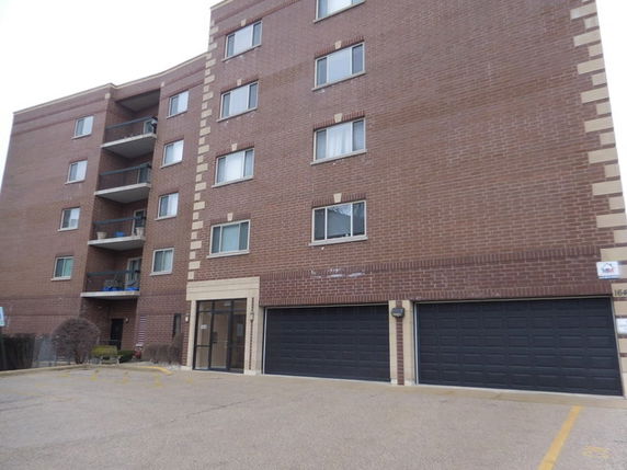 Front view of a multi-story brick apartment building with balconies.