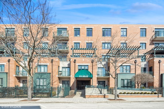 Front view of a multi-story brick apartment building with balconies.