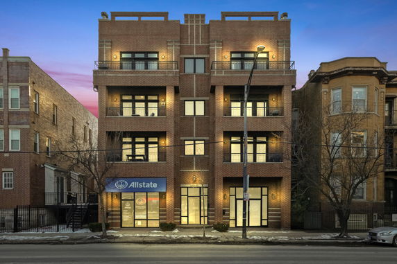 Front view of a multi-story brick building with a commercial space on the ground floor.
