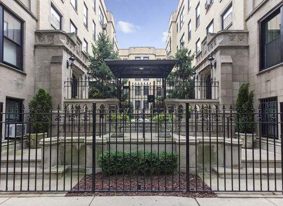 Front view of a multi-story building with decorative stonework and gated entrance.