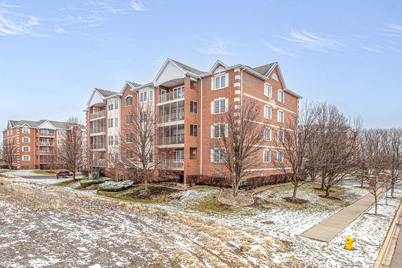 Front view of a multi-story brick apartment building with balconies.