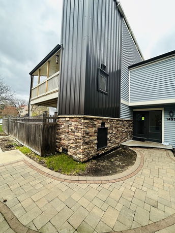 Front view of a multi-story house with a metal and stone exterior.