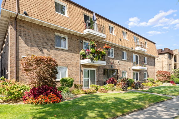 Front view of a multi-story brick residential building with balconies.