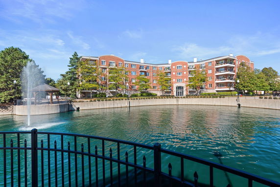 Front view of a multi-story brick building with balconies overlooking a water feature.