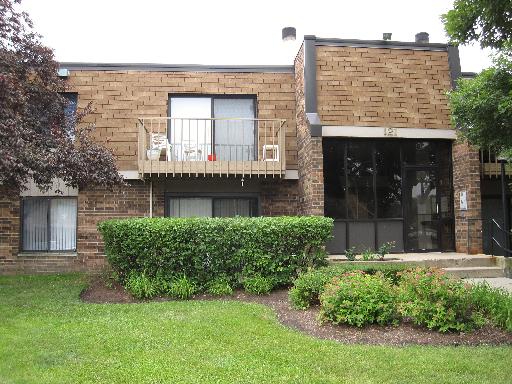 Front view of a two-story building with a balcony and brick exterior.