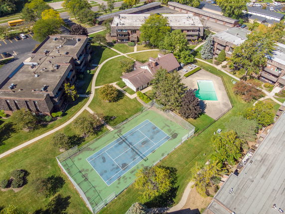 Aerial view of residential buildings with a tennis court and swimming pool.