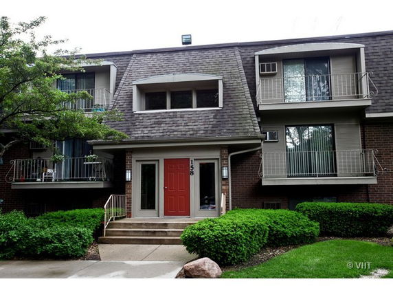 Front view of a multi-story building with balconies and a red entrance door.